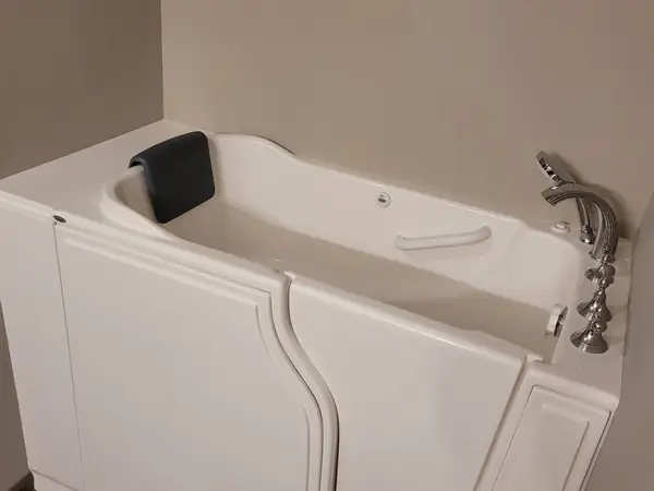 Walk-in bathtub with a hinged door against a tiled wall