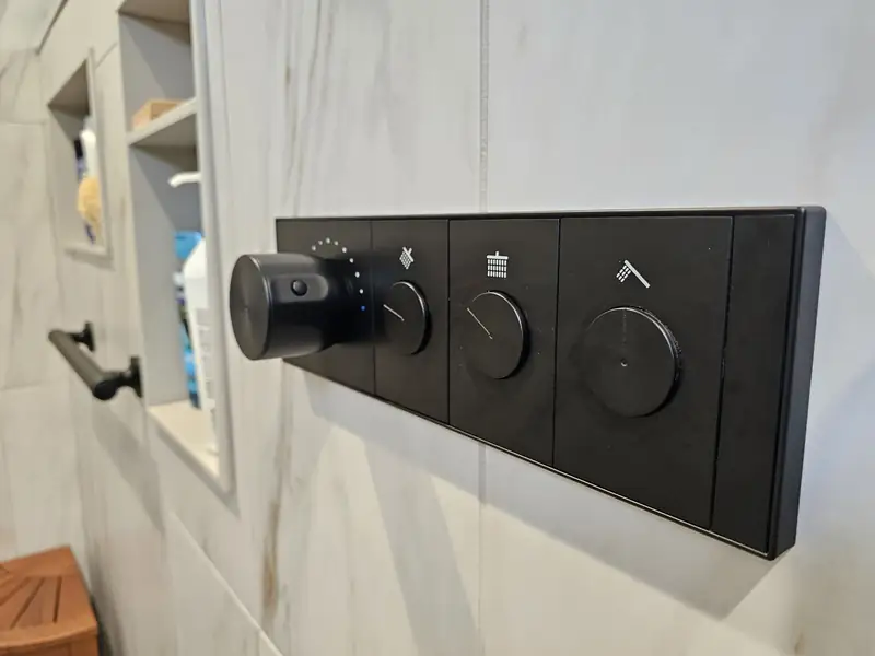 Digital thermostatic shower control panel mounted on a marble wall
