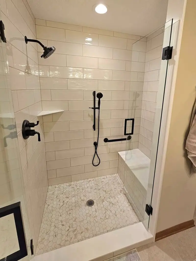 Tiled corner shower with a fold-down seat and a handheld sprayer on a slide bar