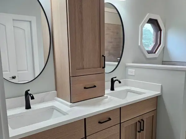 Double vanity with a wood cabinet and round mirrors