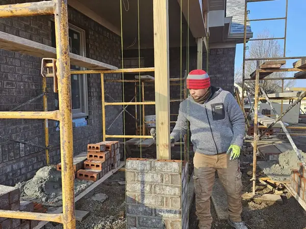Mason working on a block and brick wall from scaffolding