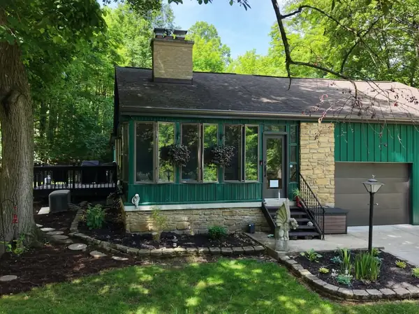 Contemporary home exterior in dark green with a stone entry column