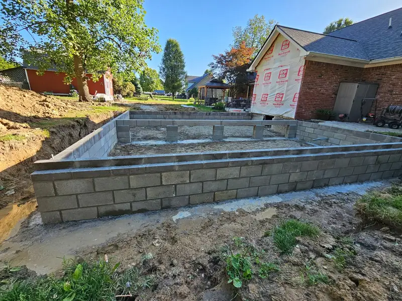 Block foundation wall completed on a new home site next to an existing house