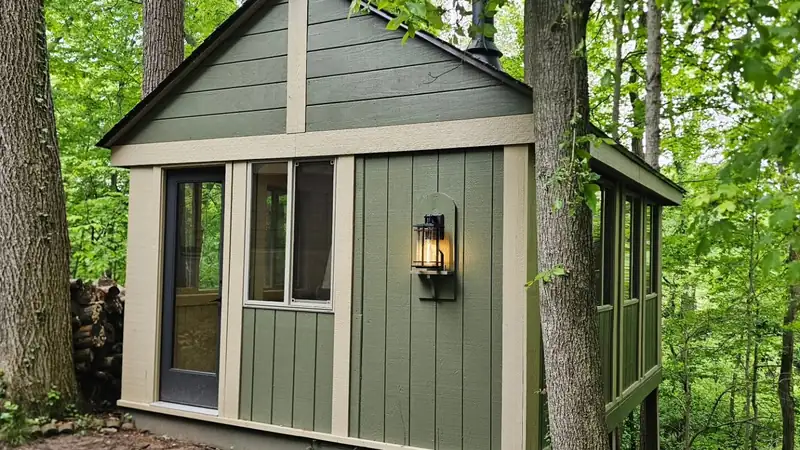 Detached studio building with board-and-batten siding in a wooded back yard