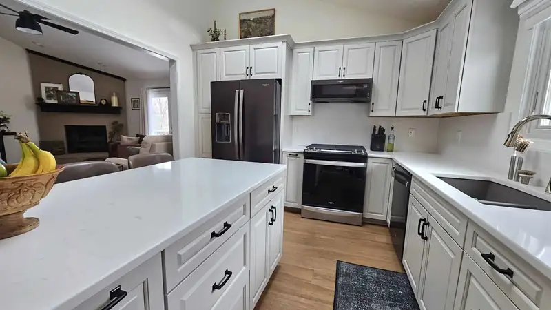 Remodeled kitchen with a large quartz island and white cabinetry
