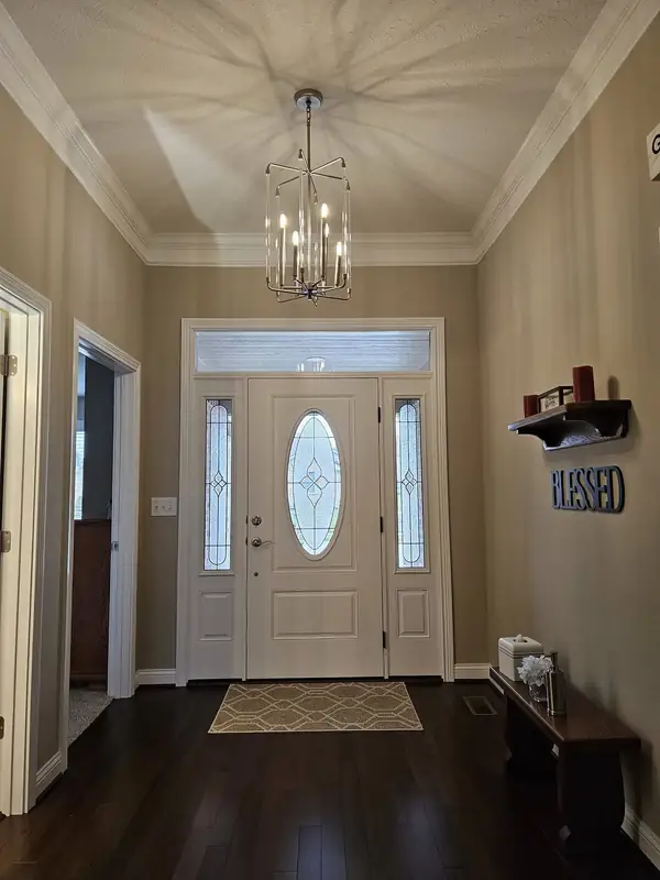 Entry foyer with a chandelier, hardwood floor and glass front door