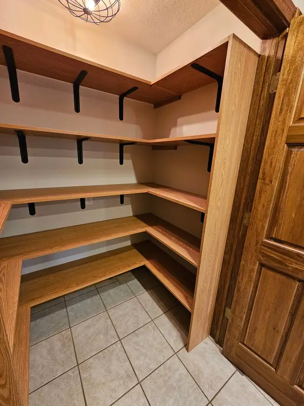Walk-in pantry with custom wood shelving on two walls