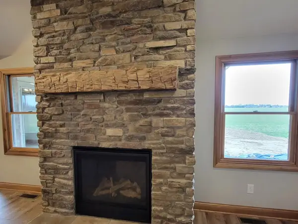 Stone fireplace with a heavy timber mantel between two windows