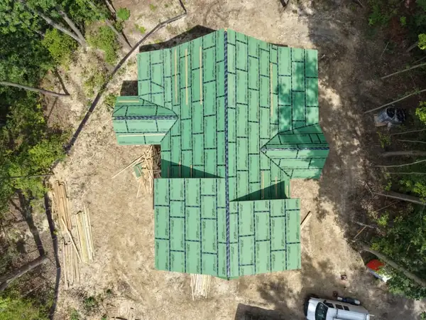 Overhead view of roof sheathing on a house built into a wooded hillside