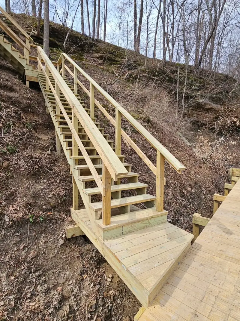 Timber staircase descending an eighty-foot wooded slope toward a lake shoreline
