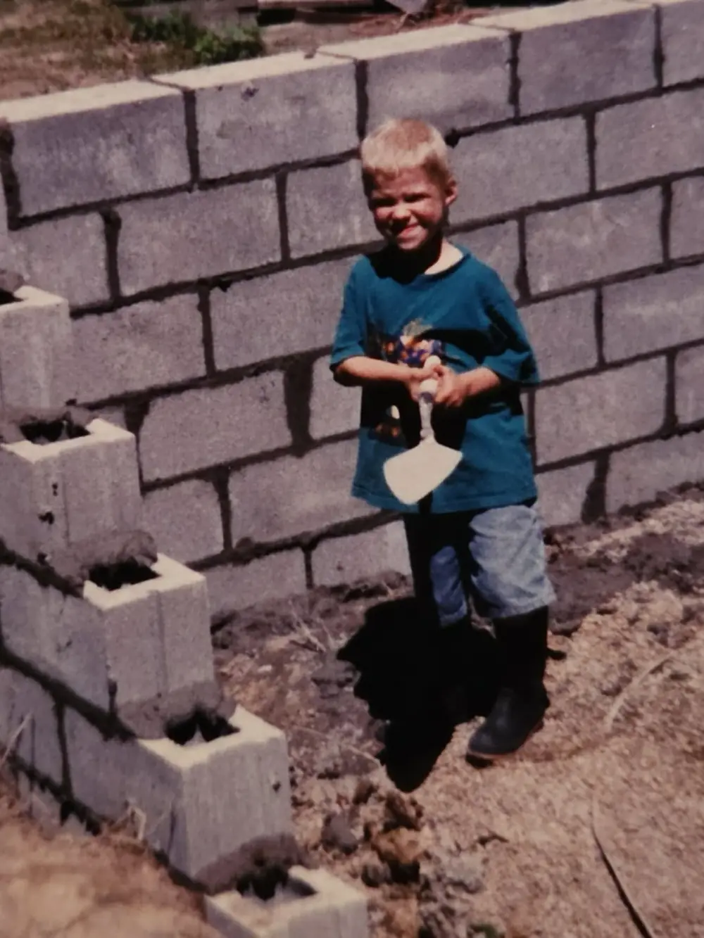 A young child standing on a new block foundation wall at a Northwood Homes job site