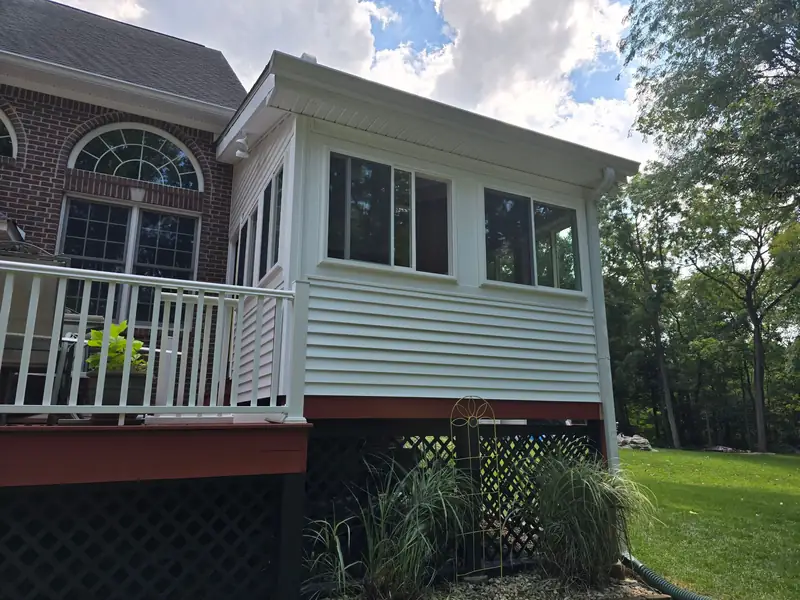 Sunroom addition on a brick home, siding and roofline matched to the original house