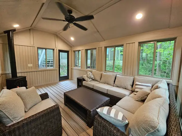 Sunroom seating area with wraparound windows and a wood stove